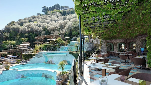 A poolside area with a pool, outdoor seating, and a view of a hillside. - Grand Hotel Capodimonte (Sorrento)