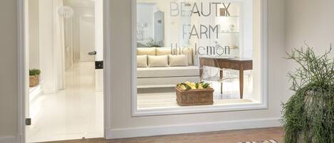 A modern interior with a large window displaying a sign for 'Beauty Farm'.