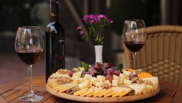 Un tagliere con formaggi, uva e noci su un tavolo di legno, accompagnato da due bicchieri da vino e una bottiglia.