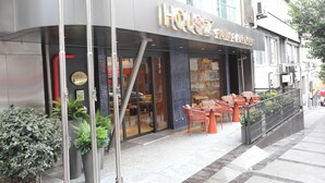 A hotel entrance with a modern design, featuring a glass facade, outdoor seating area, and a visible staircase leading to the entrance. - Housez Suites and Apartments - Special Class (Istanbul)