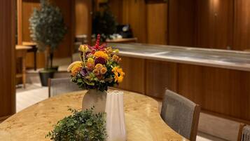 A dining area with a round wooden table, a vase of flowers, and two metallic bowls.