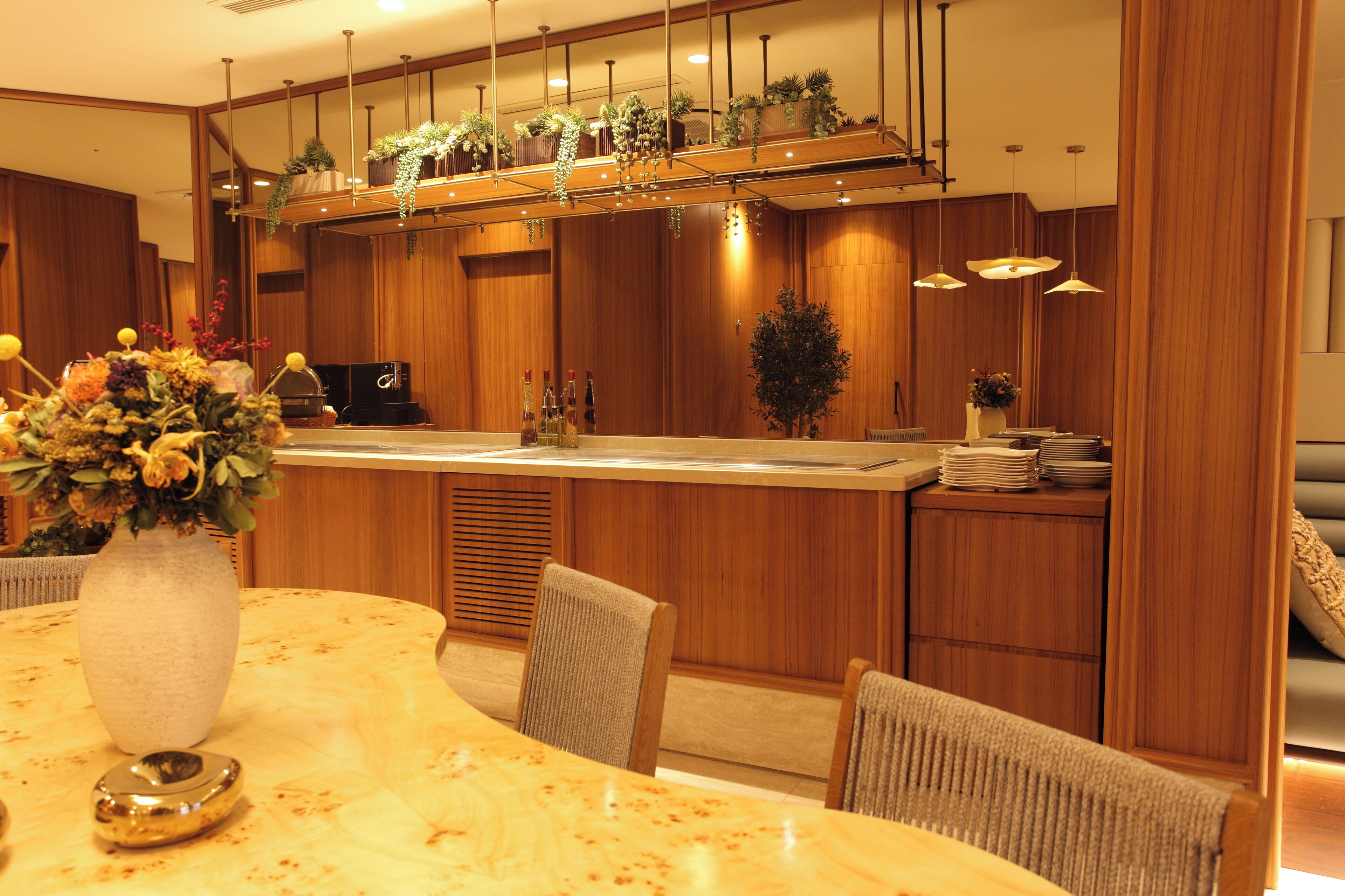 Un moderno vestíbulo de hotel con un mostrador de recepción de mármol, paneles de madera y una variedad de plantas.