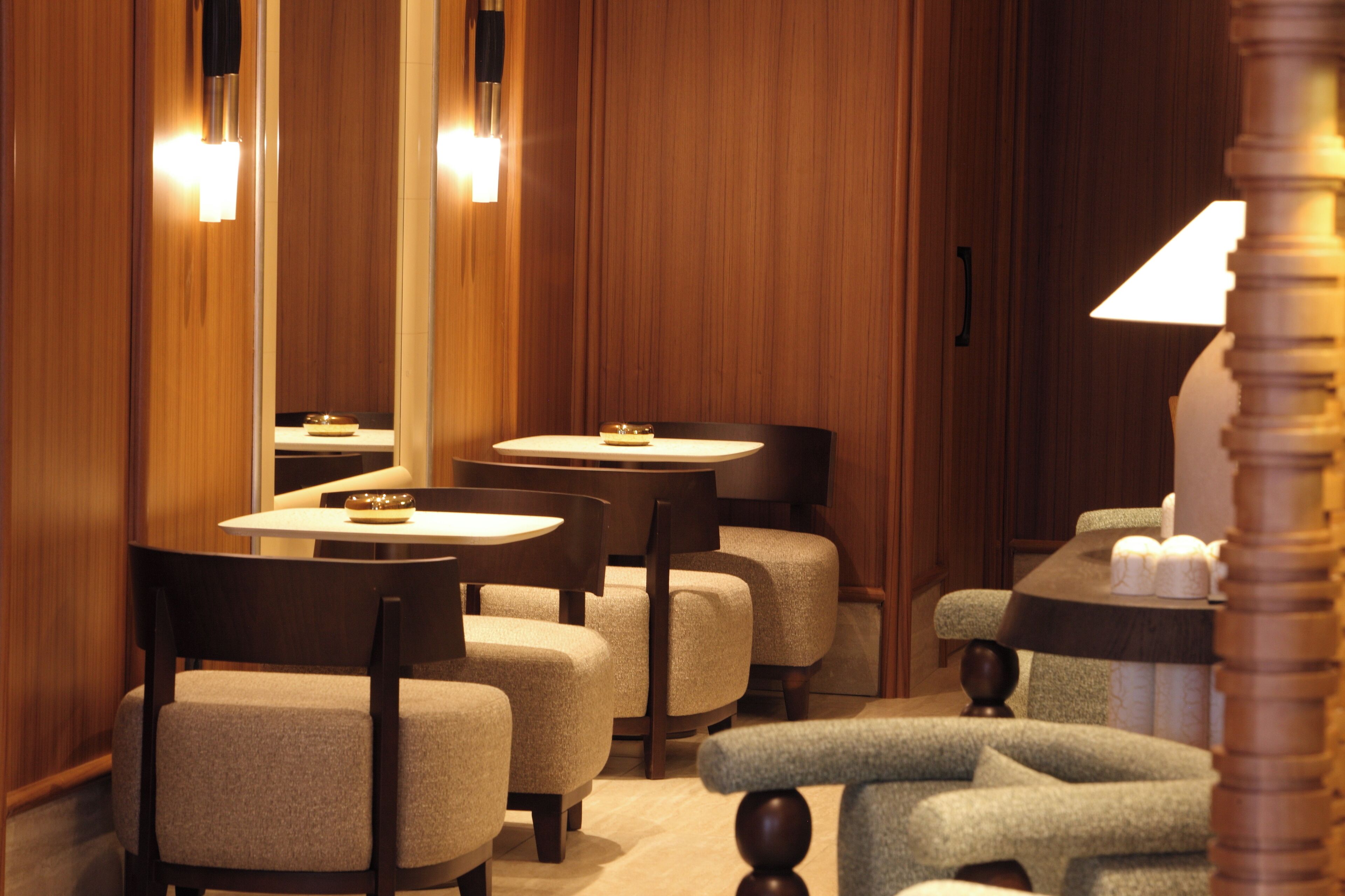 A hotel room with wooden paneling, a round table with a candle, and two upholstered chairs.