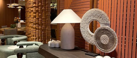 Un interior moderno con un mostrador de recepción curvo, un pilar de madera y un panel decorativo en la pared.