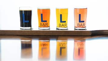 Four shot glasses with the letters "L" and "BAR" on a reflective surface.