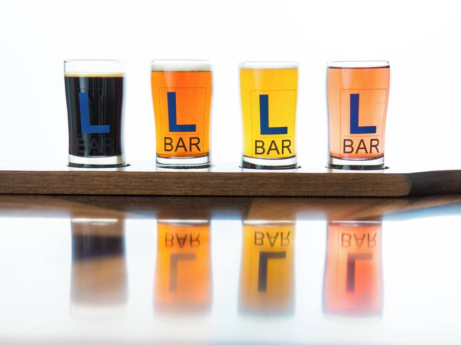 Four shot glasses with the letters "L" and "BAR" on a reflective surface.