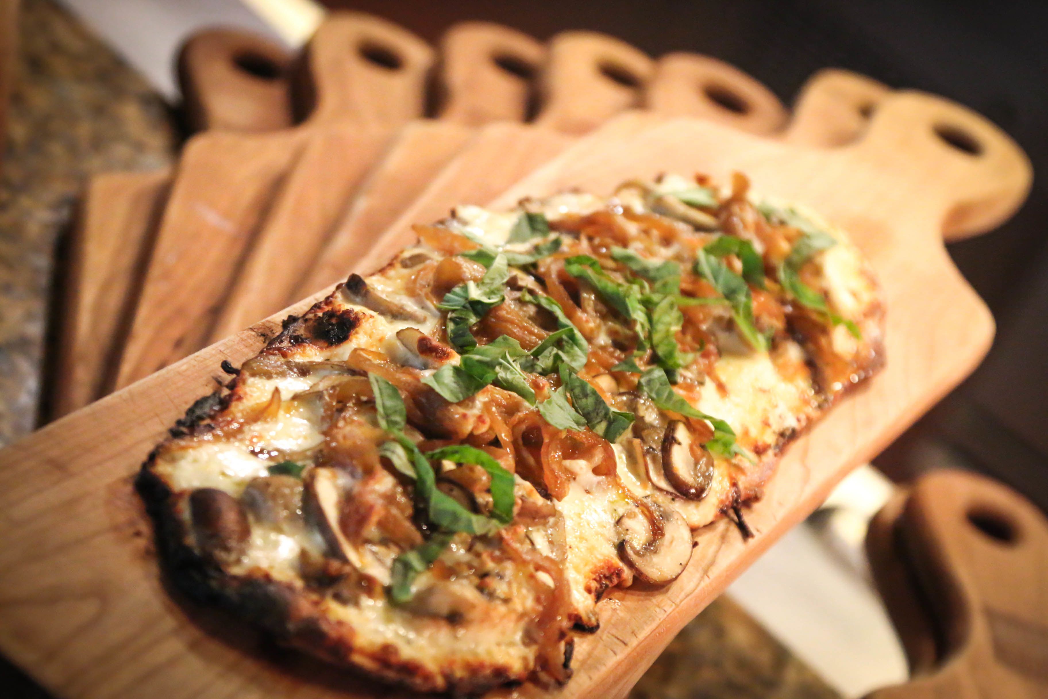 Une pizza sur une planche à découper en bois.