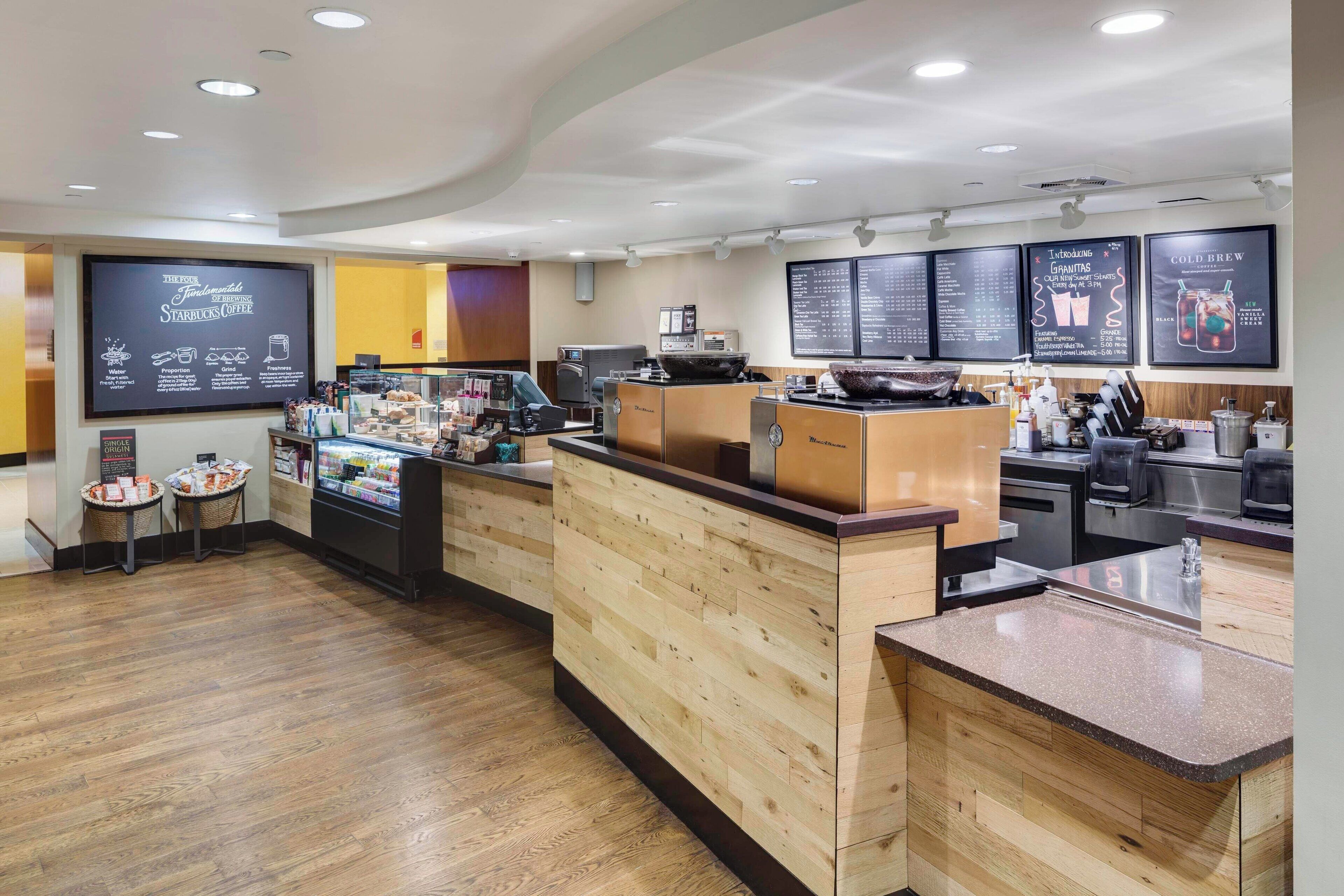 A modern coffee shop interior with a wooden counter, espresso machines, and menu boards.