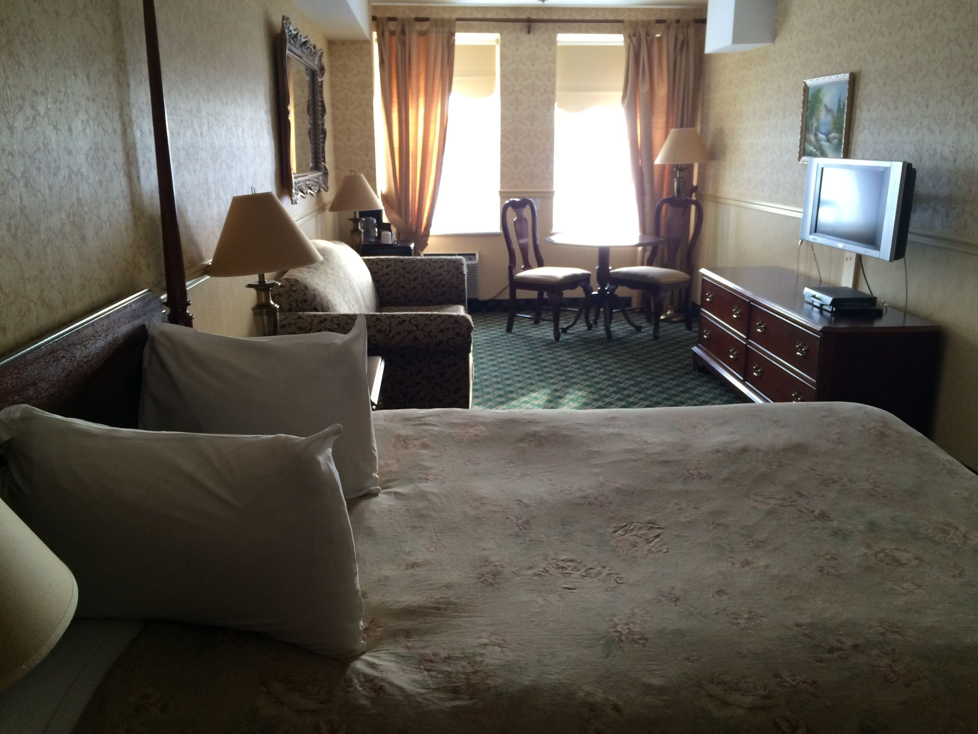 Een hotelkamer met een groot bed, een bureau, twee stoelen, een dressoir en een televisie.