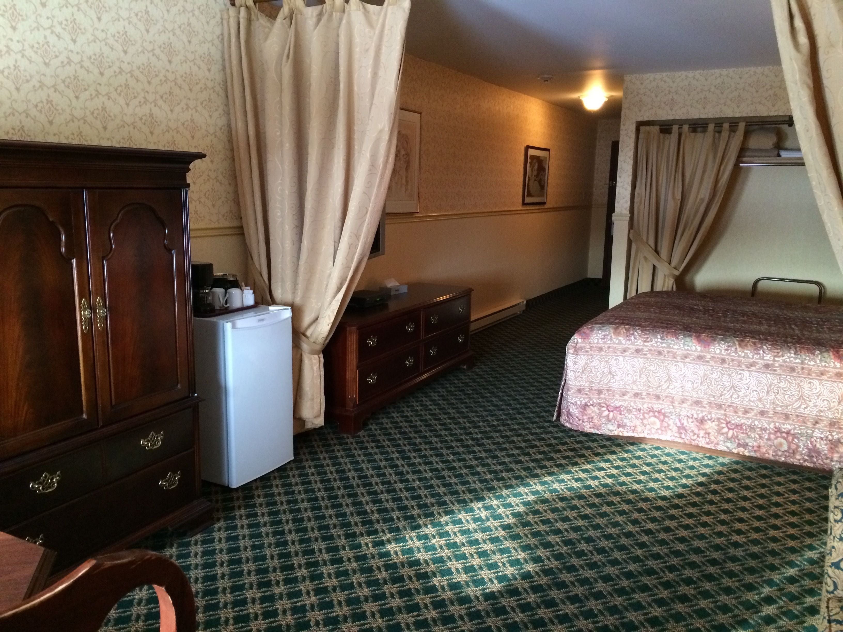 Una habitación de hotel con cama, cómoda, refrigerador y escritorio.