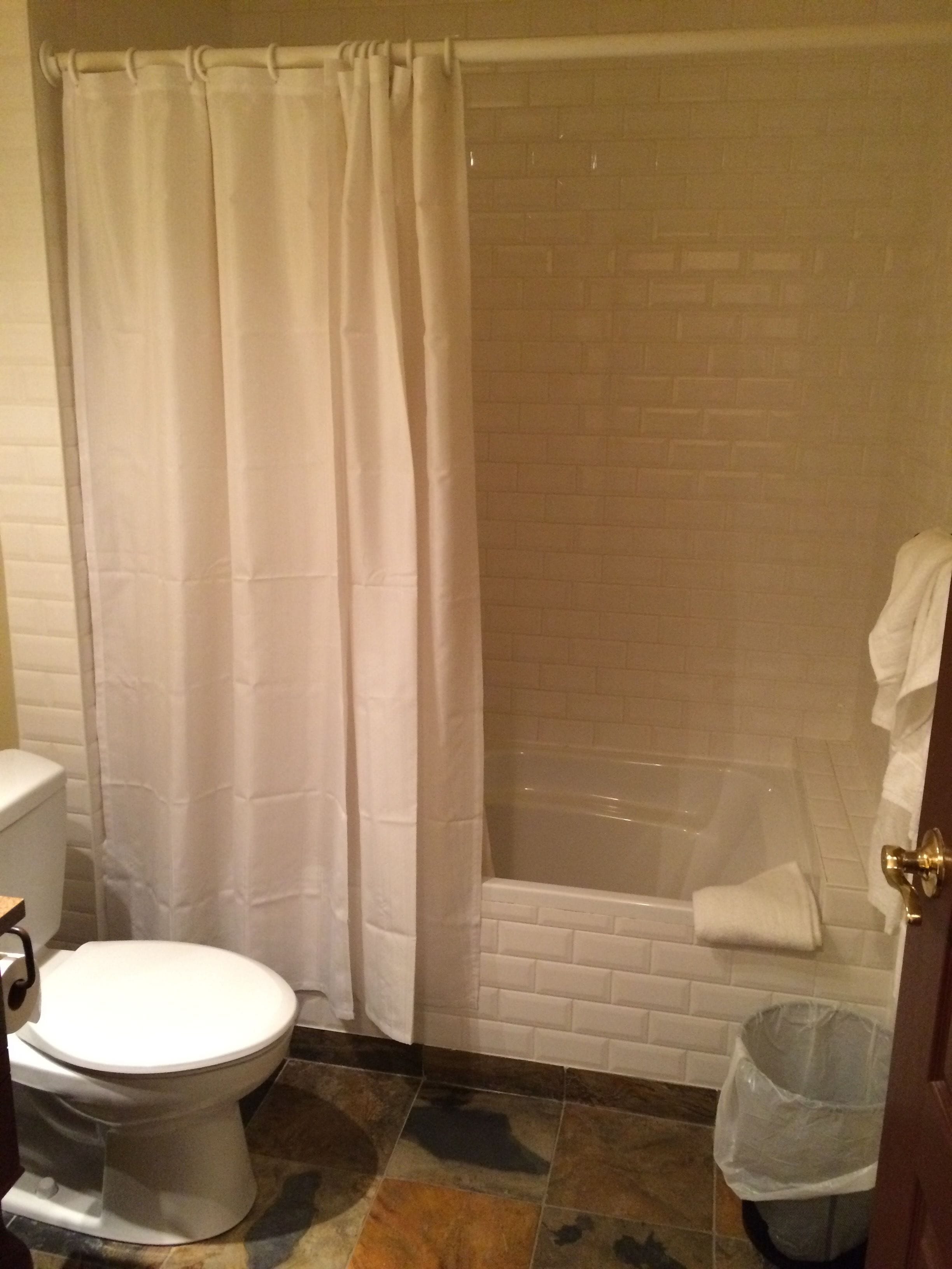A bathroom with a toilet, a shower with a glass door, and a tiled floor.