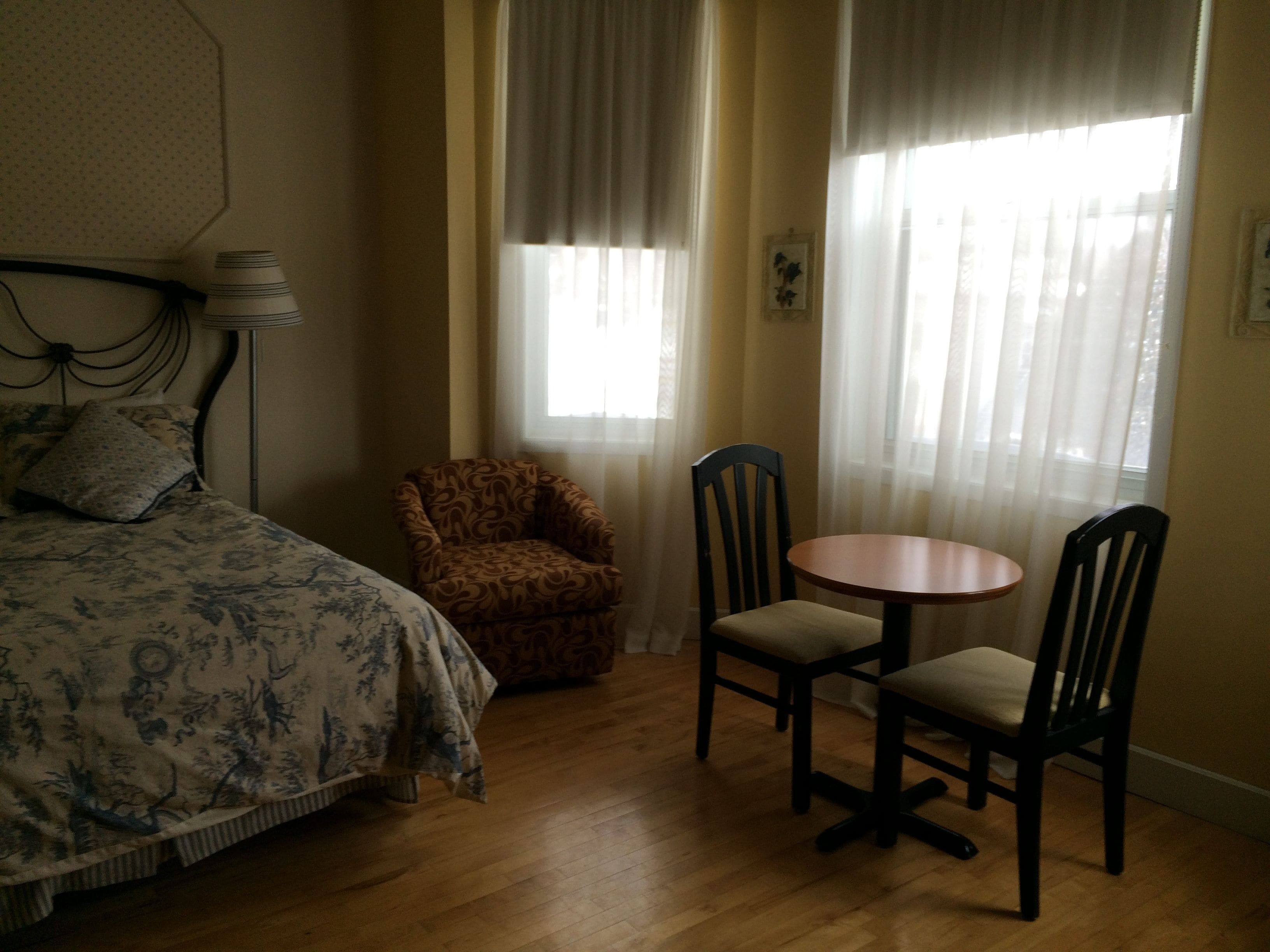 Un dormitorio con cama, una silla, una mesa y cortinas.