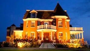 A large, two-story house with a prominent balcony and a well-maintained front yard. - Auberge Montebello (Montebello)