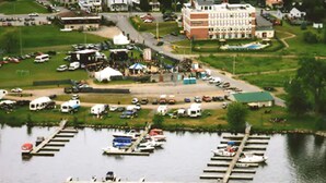 Un port de plaisance avec des bateaux amarrés, un parking pour camping-cars et un grand bâtiment doté d’un toit végétalisé.