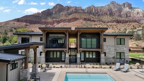 A modern two-story building with a pool, outdoor seating, and a view of mountains. - Montclair at Zion (Springdale)