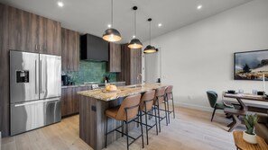 A modern kitchen with a central island, stainless steel appliances, and pendant lighting.