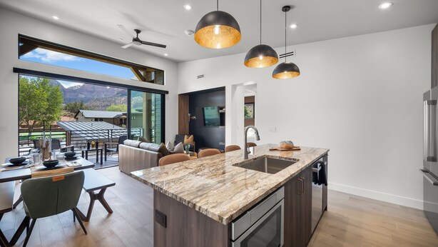 A modern kitchen with a large island, dark cabinetry, and pendant lighting. - Montclair at Zion (Springdale)