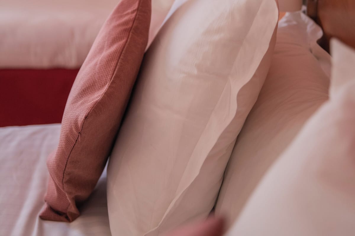 Una cama con varias almohadas y un cabecero de madera.