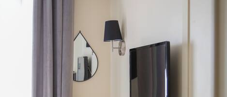 Una habitación de hotel con cama, escritorio, televisor y espejo.