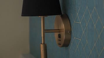En vægmonteret lampe med skærm i sort, metalbase og stikkontakt.