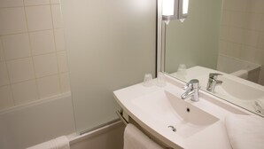 A modern bathroom with a white sink, two mirrors, a glass shower enclosure, and a wooden floor. - Ibis Perpignan Nord Rivesaltes (Rivesaltes)