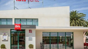 Ett modernt hotell med en tydlig skylt med texten ”ibis HOTEL”, en reception och en fasad av glas.