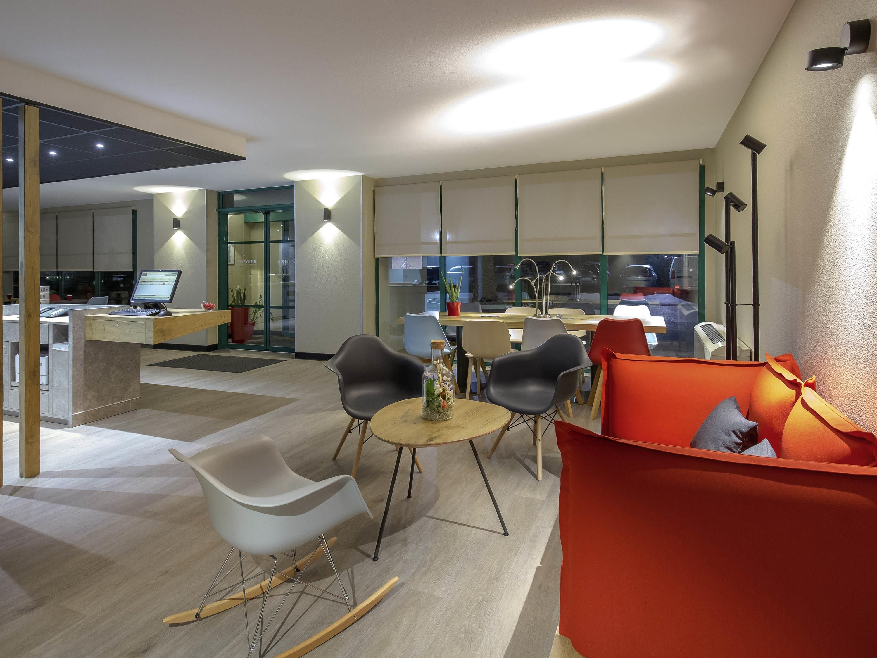Un intérieur moderne comprenant une cuisine, un coin repas et un espace détente avec un fauteuil à bascule et un canapé orange.