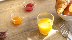 A breakfast table with croissants, a plate of cheese, ham, and salami, a glass of orange juice, a cup of coffee, and a small bowl of jam. - Ibis Perpignan Nord Rivesaltes (Rivesaltes)