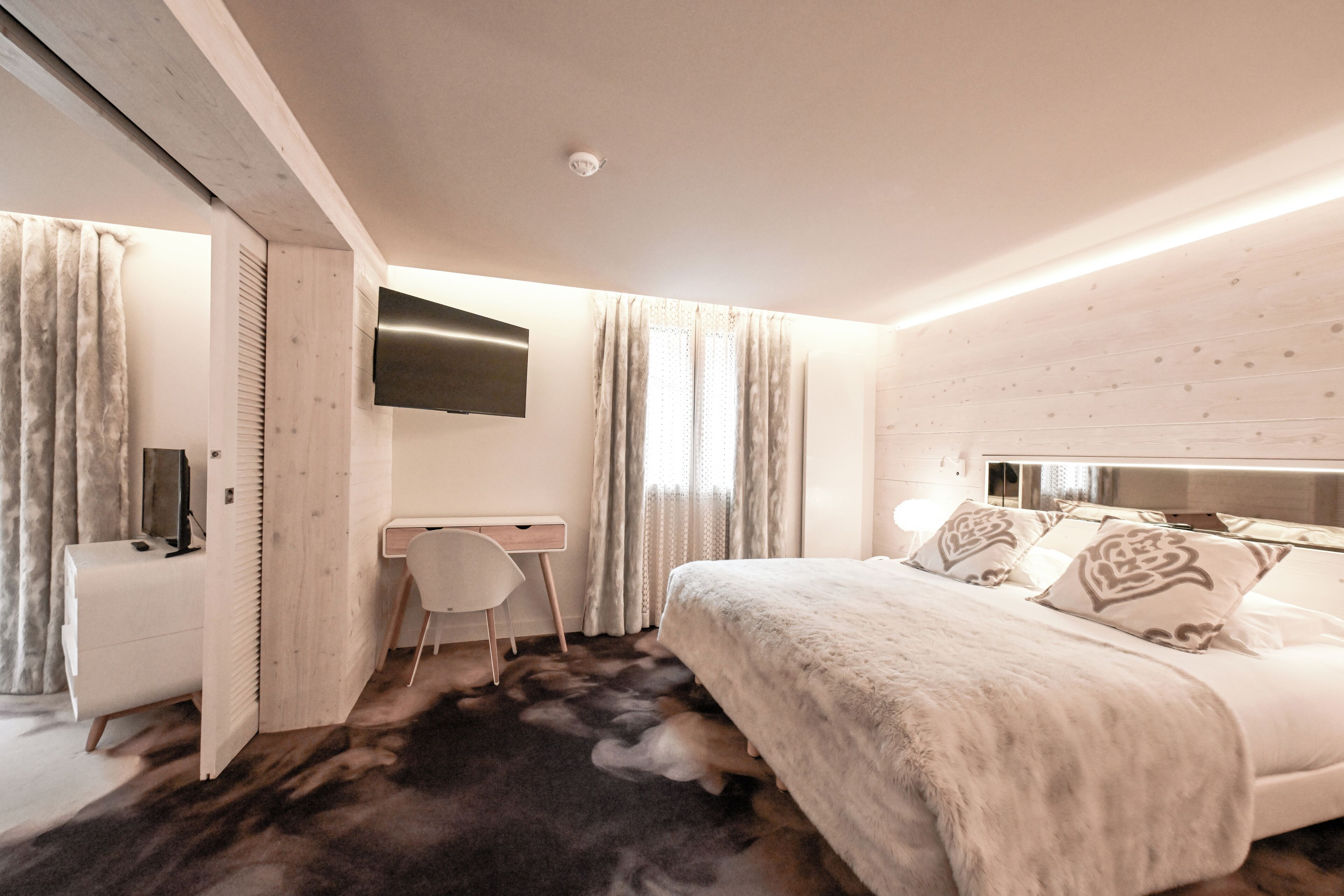 Une chambre moderne avec un grand lit, un bureau et une télévision.