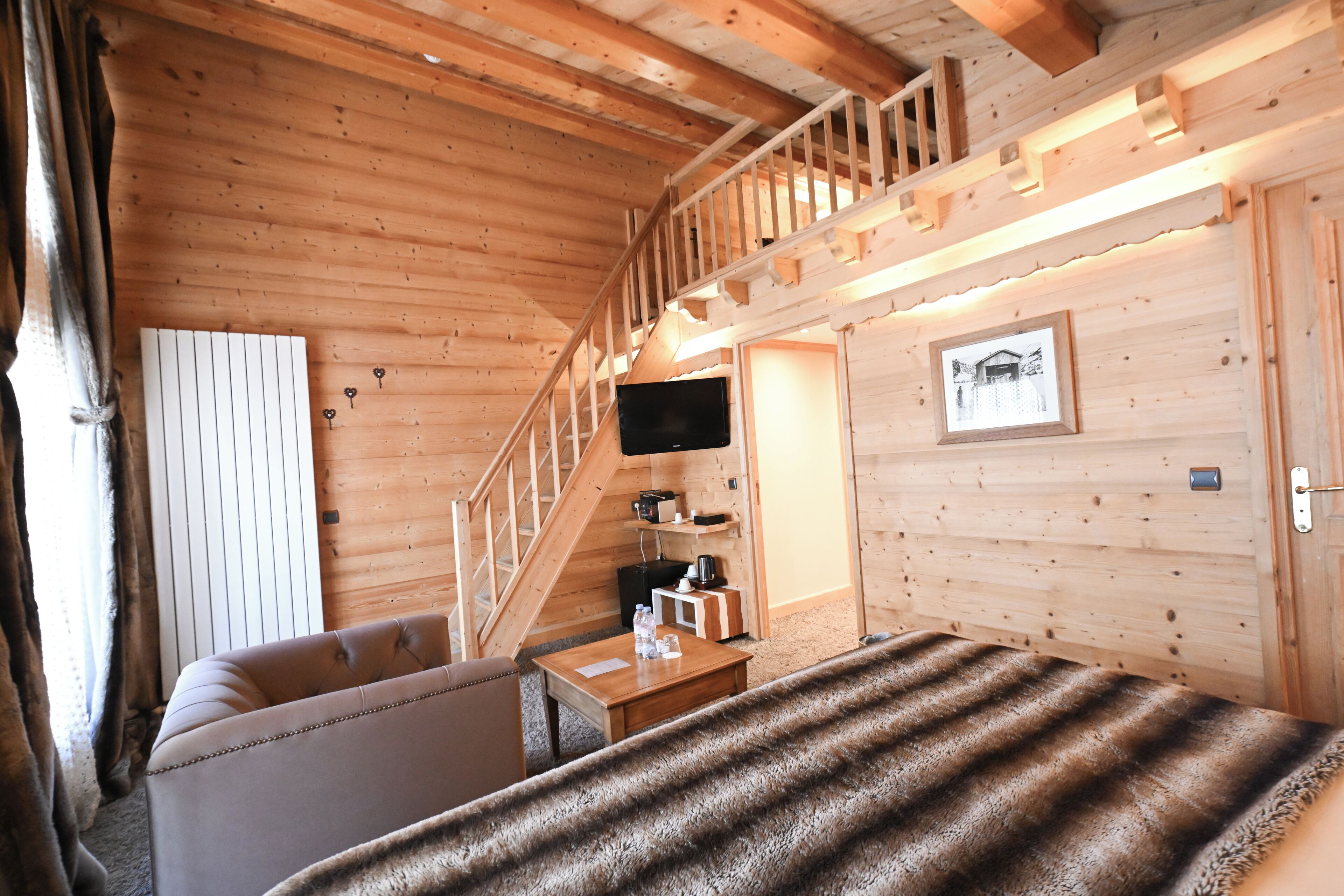 L’intérieur d’un chalet en bois, avec un canapé, une petite table, un téléviseur et un escalier.