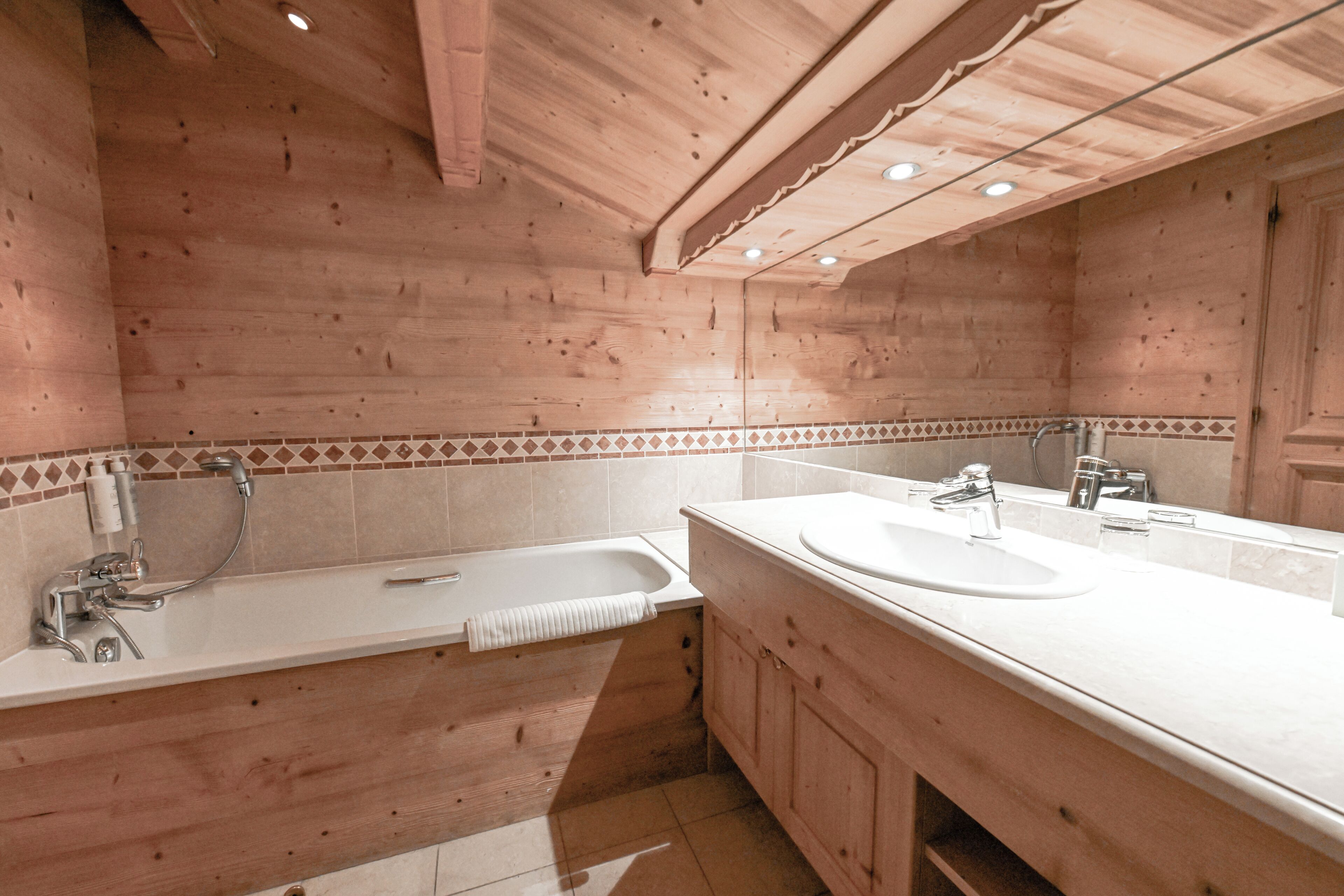 Un bagno in stile baita con vasca, due lavabi e uno specchio grande.