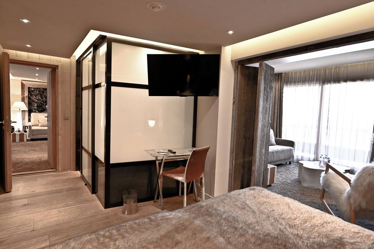 Een moderne hotelkamer met een groot bed, een bureau met stoel, een flatscreen-tv en een zithoek met een bank en fauteuils.