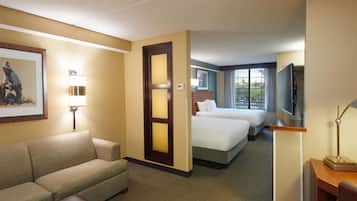 A hotel room with a sofa, a bed, a television, and a painting on the wall.