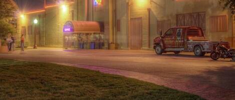 A building with a neon sign, a covered waiting area, and a parked truck.