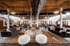 A spacious lobby with high ceilings, exposed beams, and large windows. There are multiple seating areas with sofas and a central coffee table. - Hyatt Place Fort Worth/Historic Stockyards (Fort Worth)