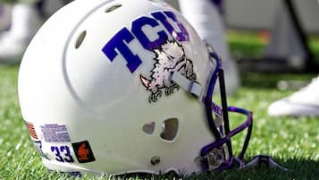 A white helmet with the letters "TGC" and a cartoon character, placed on grass.