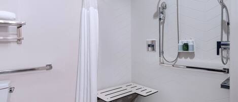 A shower area with a showerhead, handheld shower, and a towel rack.