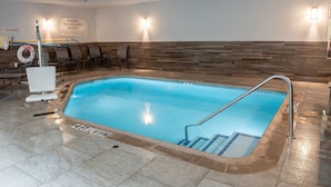 An indoor swimming pool with a wooden wall backdrop, a lifeguard chair, and a sign warning of no lifeguard on duty. - Fairfield Inn and Suites by Marriott Denton (Denton)