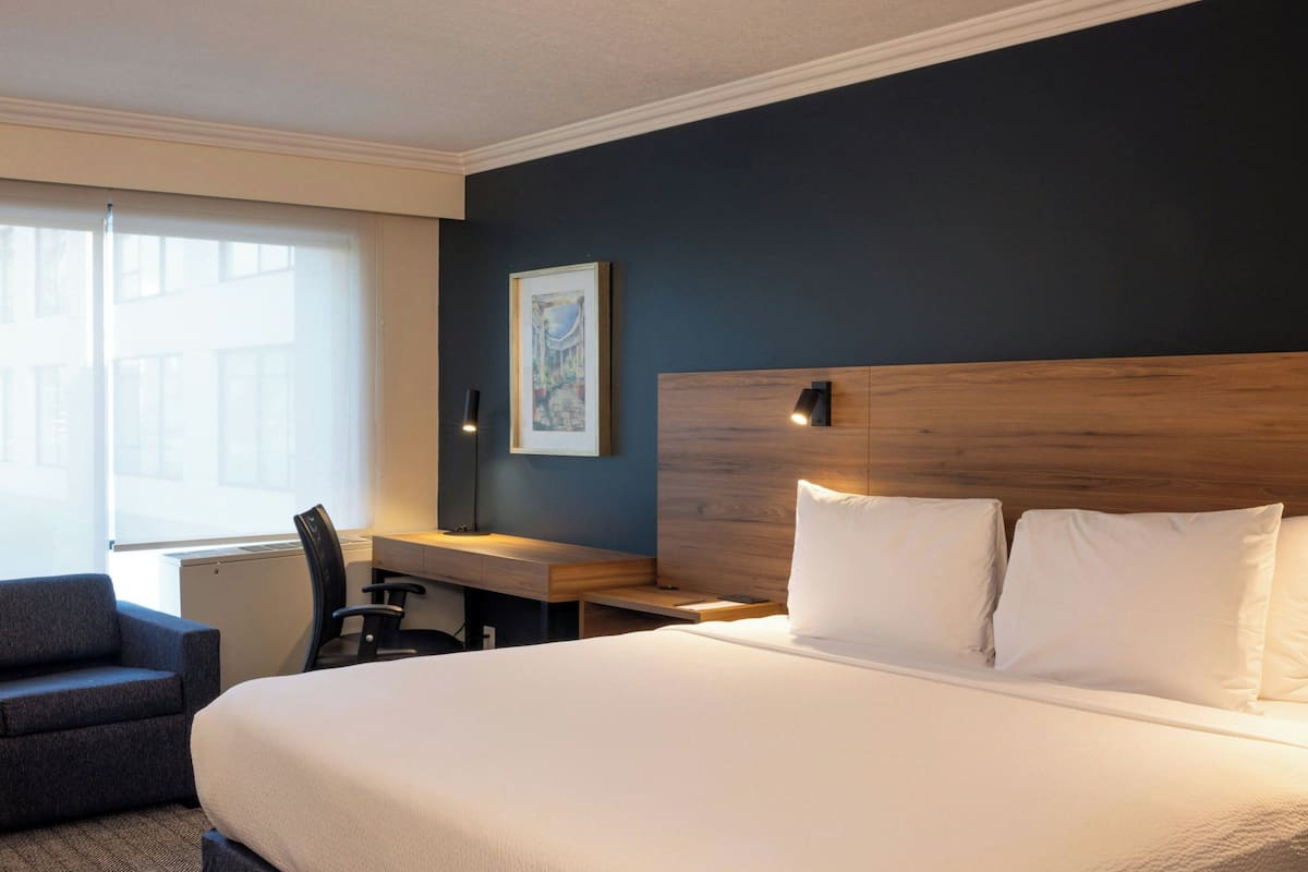Une chambre d’hôtel avec un grand lit, un bureau, une chaise et une fenêtre.