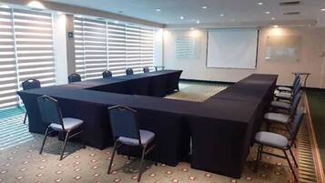 A conference room with a long table, chairs, and a projector screen.