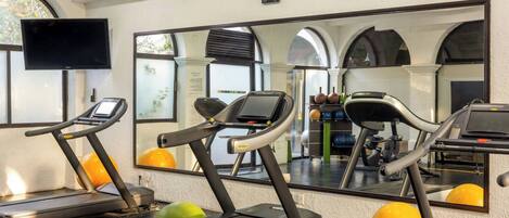 A gym with treadmills, exercise balls, and a large mirror reflecting the room.