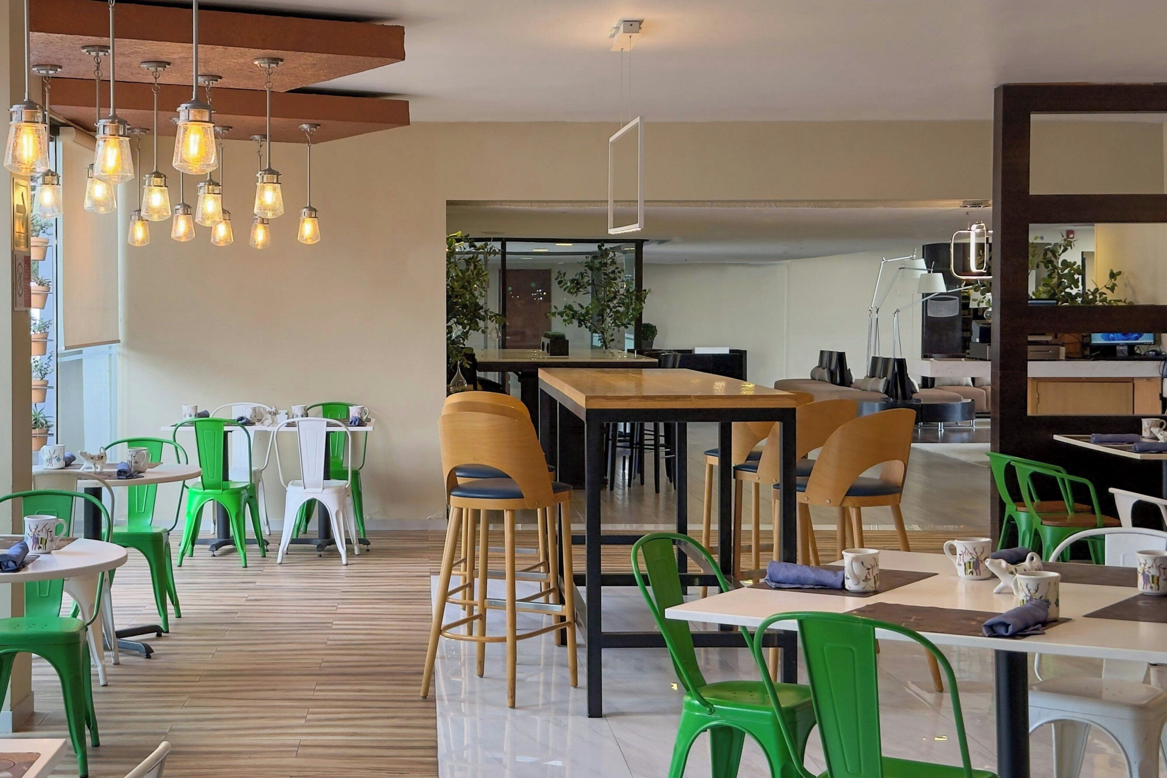 Een modern café met houten tafels en stoelen, hangende lampen en een strak, minimalistisch design.