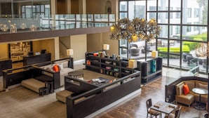 A spacious lobby with a central seating area, a reception desk, and a view of the outdoor garden through large windows.