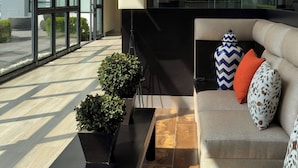 A modern living room with a sofa, a black coffee table, and potted plants.