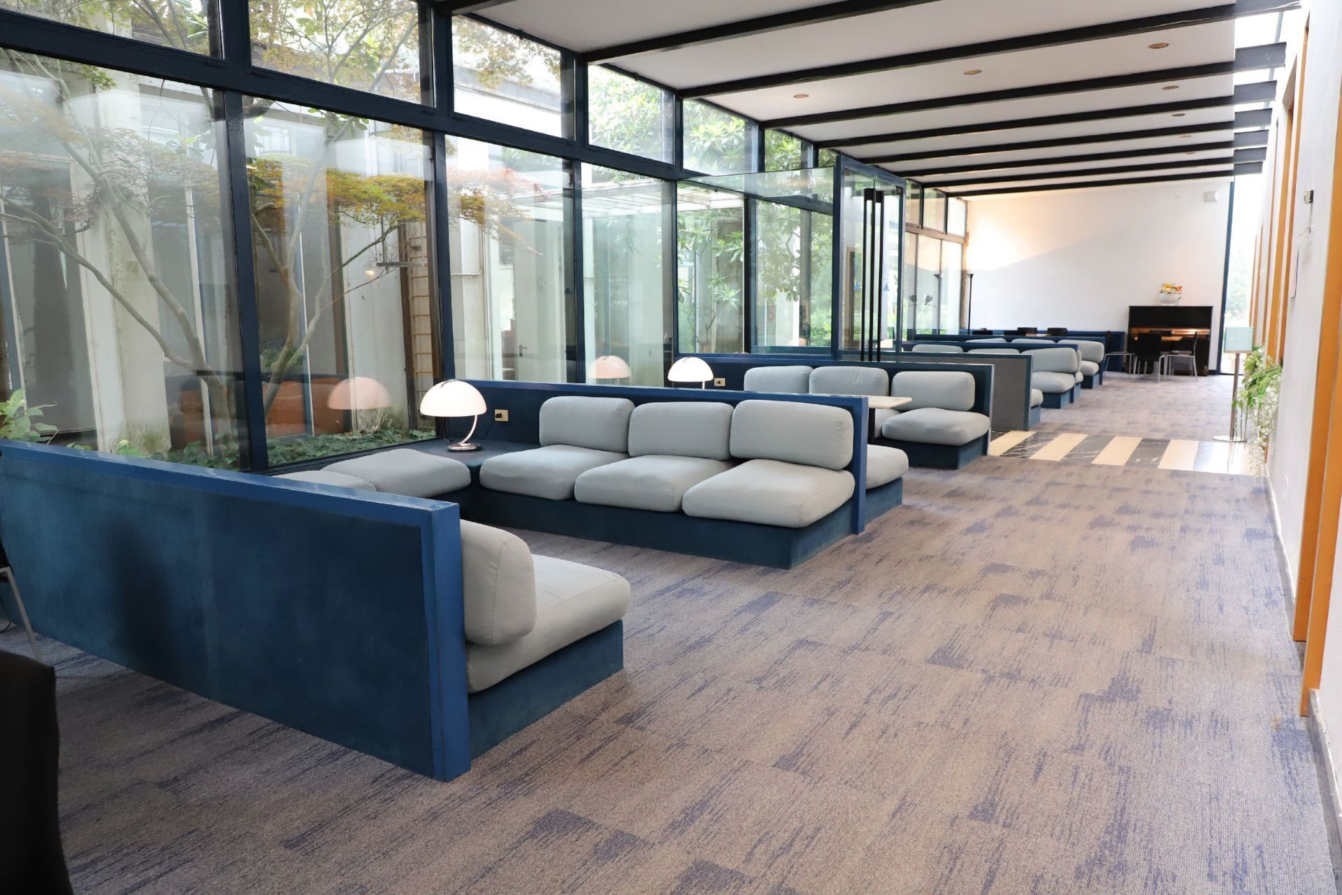 A modern waiting area with blue seating, large windows, and a carpeted floor.
