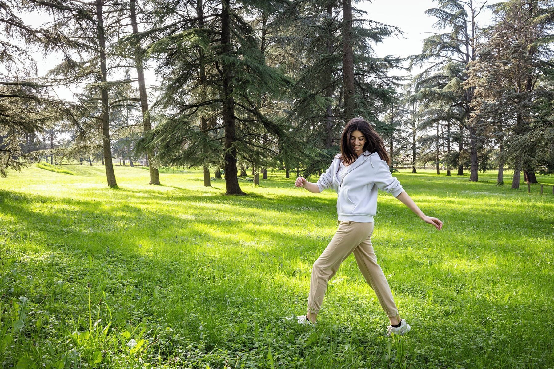 A person in a park with trees and grass.