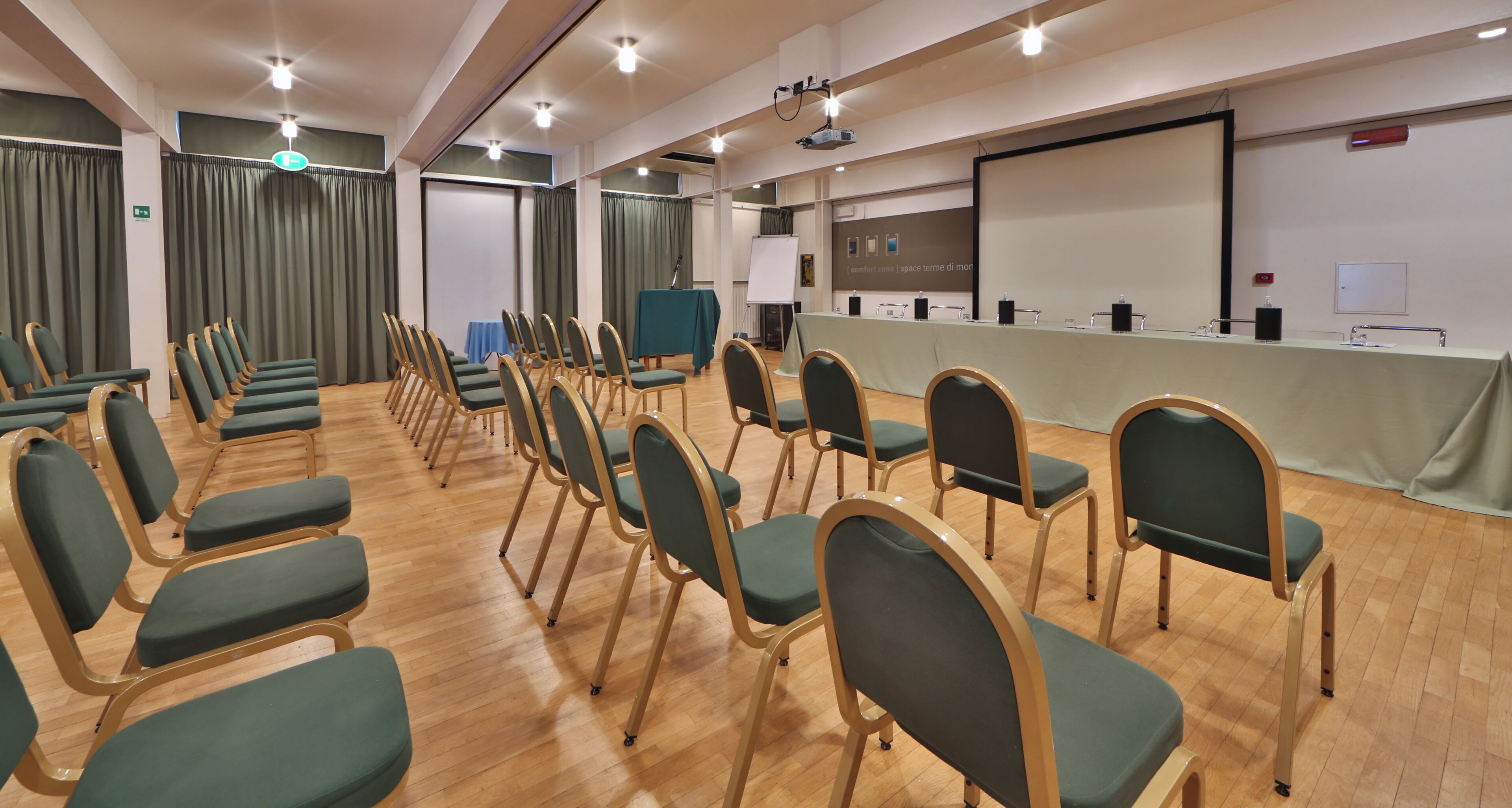A conference room with rows of chairs, a projection screen, and a whiteboard.