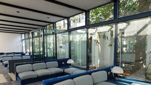 A modern interior with seating areas, large windows, and a view of greenery. - Hotel Terme (Montechiarugolo)