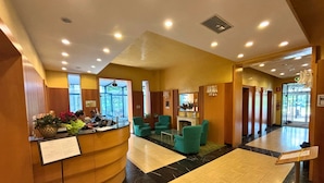 A hotel lobby with a reception desk, seating area, and a large open space. - Hotel Terme (Montechiarugolo)