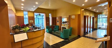 Un hall de hotel con mostrador de recepción, zona de estar y un amplio espacio abierto.